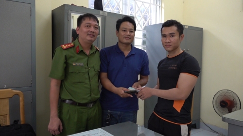 Anh Phan Văn Tiến (áo xanh dương) trao lại tài sản cho người đánh rơi là anh Lê Thanh Mãi (áo đen).jpg