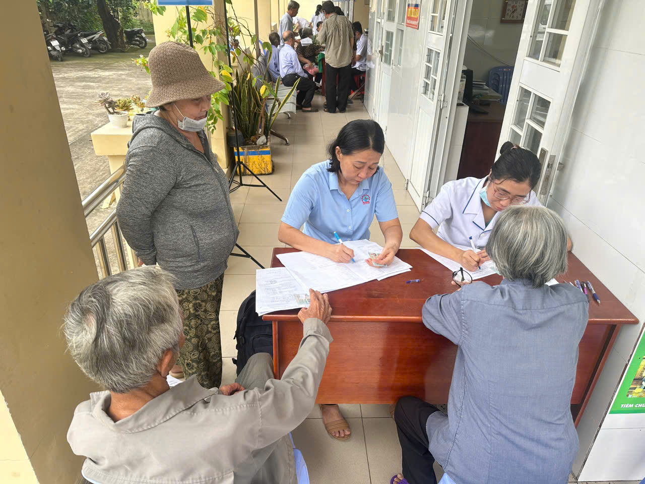 Người dân được nhân viên y tế hướng dẫn và kiểm tra huyết áp tại điểm khám.